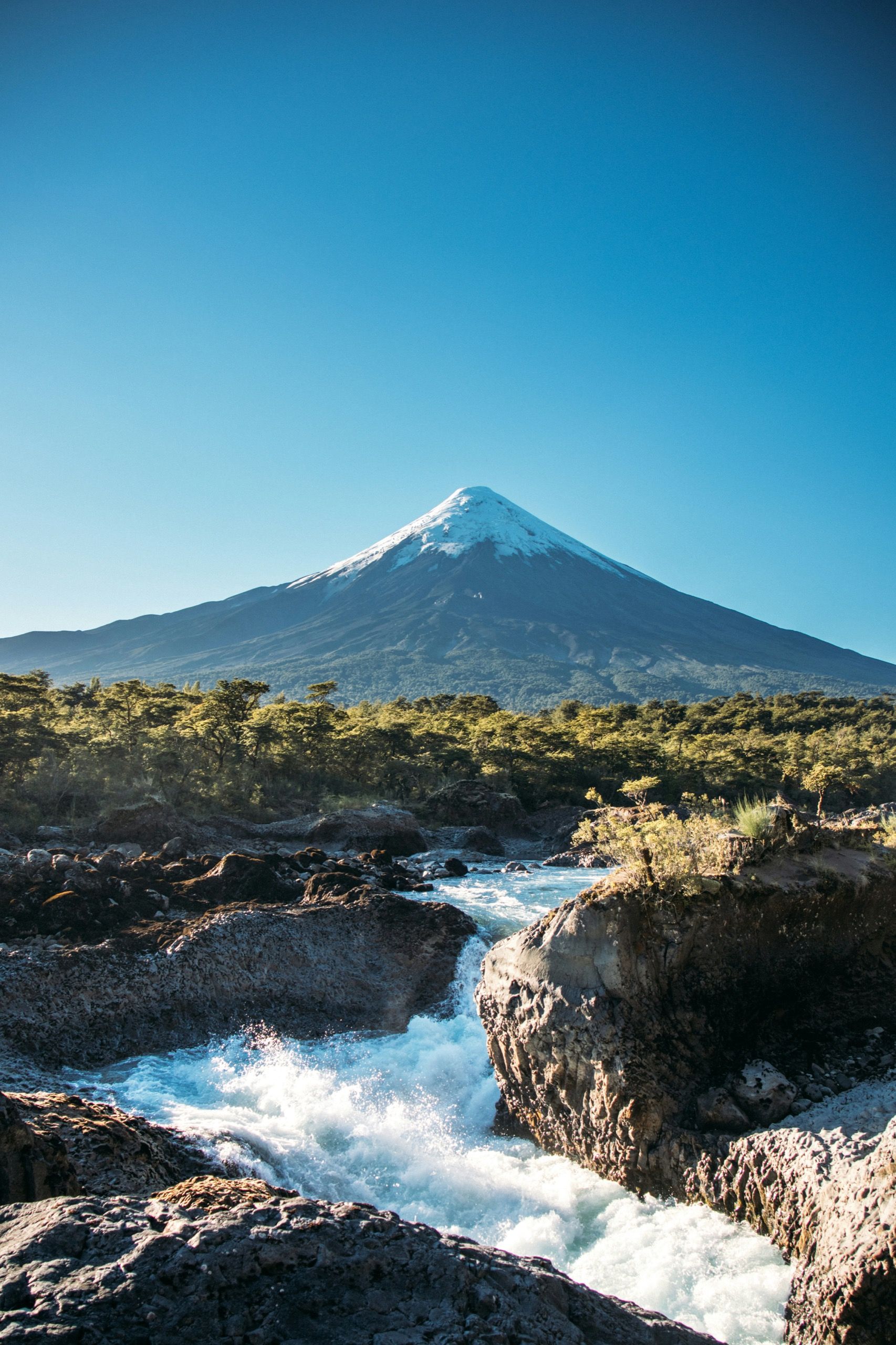 El volcán Osorno nevado visto desde los saltos del Petrohué, con el río en primer plano